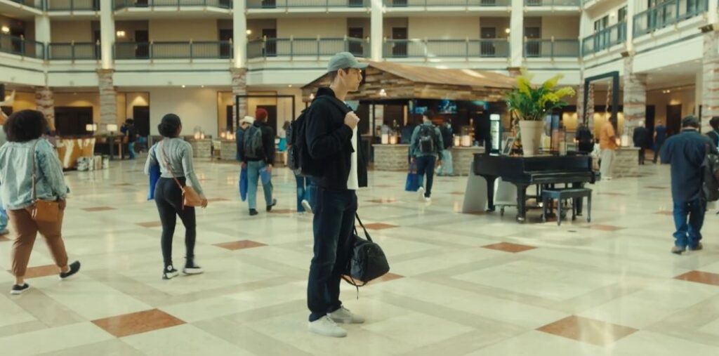 a man stands in the middle of a building lobby in the film Protocol 7