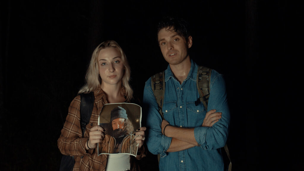 a couple hold a picture in a still from Shadows of bigfoot