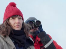 Two researchers look at something in the documentary Antarctic Voyage