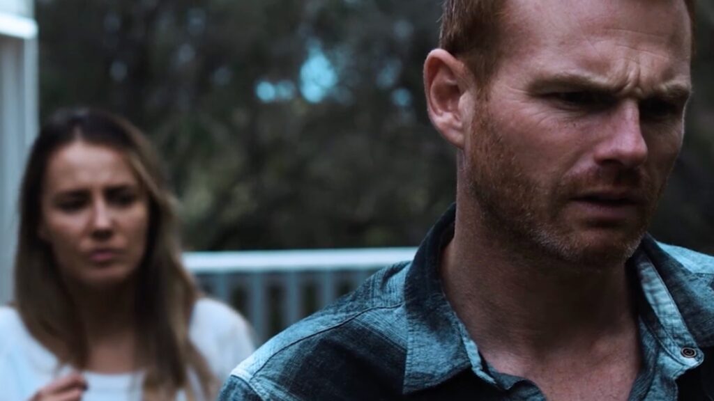 a man looks distressed while a woman stands behind him in the film the dunes