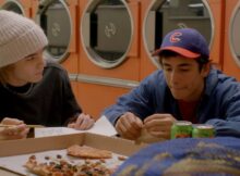 two young men eat pizza in a laundry place in the film dirty laundry