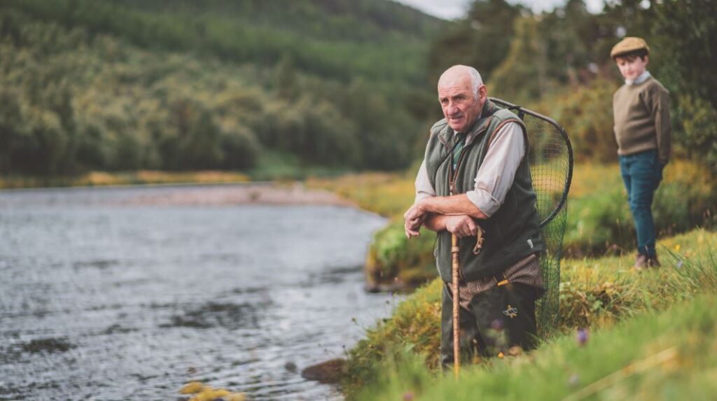 An old man kneels beside a lake in the last keeper